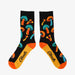 Black socks covered in bold, colorful mushrooms in orange, teal, and yellow hues, with bright orange toes and Aksels logo on the sole.